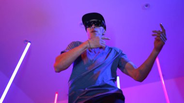 Beyaz dansçının gösterişli gözlükler taktığı ve break dans yaptığı alçak açılı kamera. Çekici adam kendinden emin bir şekilde kameraya bakarken enerjik bir performans ve hareket gösterdi. Mutluluk.