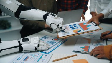 Bir robot kol, bir grup profesyonele veri analizinde, teknoloji ve insan işbirliğinin dinamik ofis ortamında entegrasyonunu göstermede yardımcı olur. Noogenesis