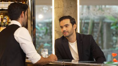 Tezgahta oturup barmenle konuşan zeki müşteriler gece kulübü lüksünde içki listesi tavsiye eden profesyonel barmen kostümü için harika bir izlenim bırakıyorlar. Vinosity.