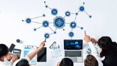 Bir çalışma alanı üzerinde veri analizi ve teknoloji unsurlarının yer aldığı bir iş stratejisi oturumunda yer alan bir grup profesyonel, işbirliği ve yeniliği destekliyor. Dostluk