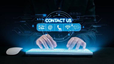 Bir insan eli, iş bağlamında modern dijital iletişimi gösteren, temas simgeleriyle parlayan fütüristik bir klavyeye yazı yazıyor. Dörtgen