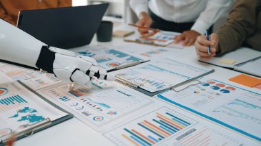 Profosyonel bir ekibe çizelgeleri, grafikleri ve raporları analiz etmede yardımcı olan modern bir iş sahnesi. Noogenesis