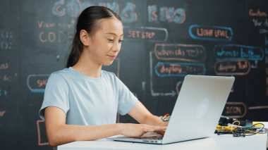 Kara tahtada dizüstü bilgisayar kullanarak akıllı kız programlama sistemi. Lise öğrencisi BTMM teknoloji sınıfında ekrana bakarken mühendislik kodu yazıyor. Yaratıcı eğitim. Öğretim.