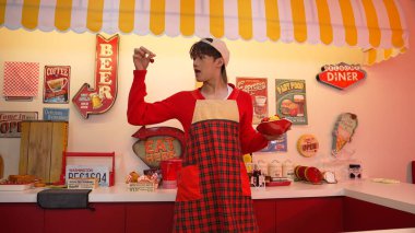 Profesyonel Asyalı restoran işçisi yemek hazırlar ve yemek barının arkasında durur. Kırmızı önlüklü çekici garson kameraya bakarken vişne topluyor. Çılgın dans. Mutluluk.