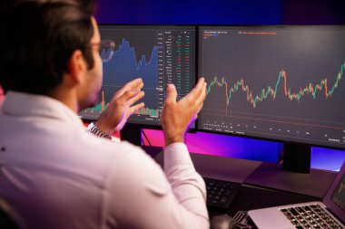 Akıllı tüccar işadamı, karanlık oda gecesinde neon ışıklı ofisteki arama pazarında yüksek kârla ekranda bilgisayar ve bilgisayar üzerinde dinamik borsa yatırımları üzerinde yoğunlaşıyor. Tahmin et..
