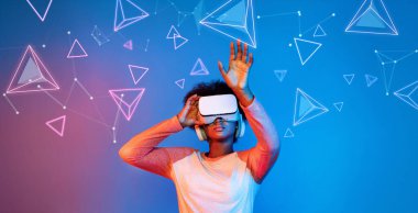 VR gözlüklü Afrikalı kız mavi ve pembe arka planda duruyor ve yüzen geometrik şekle bakıyor. Heyecanlı insan görsel gerçeklik dünyasına giriyor. Teknoloji yeniliği. Yaratıcılık.