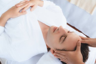 Beyaz adam stres önleyici kafa masajından ve lüks bir tatil beldesi veya otel spa salonundaki modern ışık ortamında yüz güzelliği eğlencelerini şımartmaktan hoşlanıyor. Sessiz.