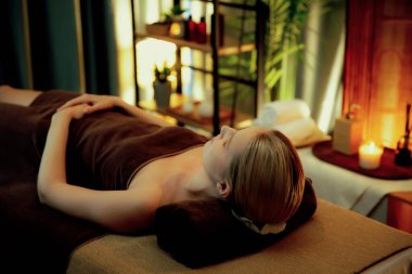 Beyaz kadın müşteri stres önleyici spa masajının keyfini çıkarıyor ve lüks otel ya da otelde sıcak mum ışığında güzellik teniyle eğleniyor. Sessiz.