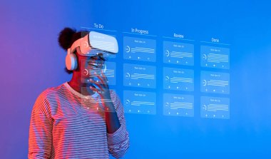 Bir kadın, yenilikçi teknoloji ve dijital araçlarla görev yönetimi ve proje planlaması yapan canlı bir ofis ortamında sanal gerçeklik kulaklığı kullanıyor. XDMCP