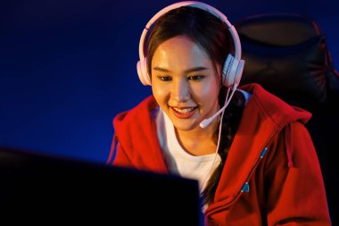Portre sunucusu güzel Asyalı kız flamasının çevrimiçi oyun oynaması kulaklık takması pastel renkli konuşmalar izleyici medyası ile çevrimiçi. Esport yetenekli takım oyuncuları neon mavi odada. Taktik.