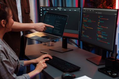 Modern ofisteki neon ışık odasında bilgi ağını gösteren dizüstü bilgisayarla iki ekranda veri çalıştıran akıllı web sitesi geliştirme kodlayıcı sistemini tartışan IT geliştiricilerinin ciddiyeti. İnfobahn.