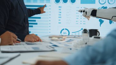 Bir robot asistanın veri analizlerini ekranda sunduğu ve teknolojilerin işyeri verimliliğinin artırılmasındaki rolünü vurguladığı bir iş toplantısını gösteren dinamik bir sahne. Noogenesis