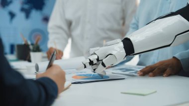 Bir robotik kol, verileri analiz edip raporları hazırlayan, gelişmiş teknolojinin işbirlikçi bir ofis ortamında entegrasyonunu gösteren bir iş ekibine yardım eder. Noogenesis