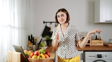 Enerjik beyaz anne kahvaltı için salata pişirirken ve yemek pişirirken elinde kepçeyle şarkı söylüyor. Sağlıklı yemek yapmaya hazırlanırken müziğe yönelen mutlu ev sahibi. Pedagoji.
