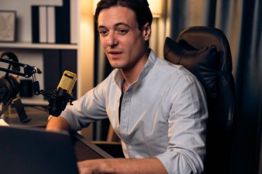 Sunucu kanalı akıllı yayıncı laptopta canlı sosyal medya uygulaması arıyor, kulaklık takıyor ve modern ofis stüdyosundaki mikrofonu kullanıyor. Bireysel.