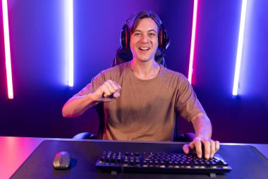 Kazanmak için çevrimiçi oyun oynayan akıllı flama makinesinin sunucu kanalı, neon ışıklı odada seçilen takım yarışması için izleyicilerle birlikte canlı yayında canlı yayında kulaklık takıyor. Bireysel.