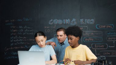 Kafkas öğretmeni mühendislik kodlarını öğretirken dizüstü bilgisayarı gösteriyor. Lise öğrencisi mutlu bir şekilde öğrenirken ve programlama sistemini öğrenirken bilgisayar kullanarak çalışan eğitmen. Öğretim.