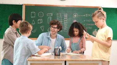 Zeki öğretmen, çeşitli çocuklar sınıf çalışması yapmak için birlikte çalışırken farklı çocukların zihin haritası çizdiği fikri açıklıyor. Çekici eğitmen öğretmek ve çalışmak hakkında konuşmak. Pedagoji.