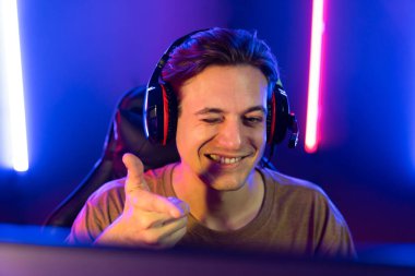 Kazanmak için çevrimiçi oyun oynayan akıllı flama makinesinin sunucu kanalı, neon ışıklı odada seçilen takım yarışması için izleyicilerle birlikte canlı yayında canlı yayında kulaklık takıyor. Bireysel.