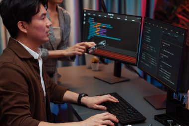 Bilgi teknolojisi geliştiricileri modern ofisteki neon ışık odasında verileri çevrimiçi olarak çalıştıran akıllı web sitesi geliştirme kodlayıcı sistemine işaret ediyorlar. İnfobahn.