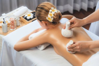 Sıcak bitkisel top spa masaj vücut tedavisi, masör kadın vücuduna nazikçe şifalı bitki torbası bastırıyor. Aromaterapi dinlenme sükuneti ve sükuneti kaplıca salonundaki atmosferi aydınlatıyor. Sessiz.