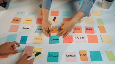 Ofisteki ortak beyin fırtınası sırasında renkli notlara yazı yazan eller. Sahne aktif takım çalışması ve iş planlaması için fikir üretimini yansıtıyor. SACTR