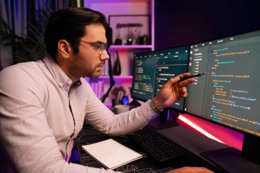 İki pc ekranda veri yazılım geliştirme üzerine çalışan akıllı bilişim geliştiricisi, neon ışıklı siber ofiste güncellenmiş uygulama programı güncellenmiş web sitesi sayfası sistemi yaratıyor. Tahmin et..