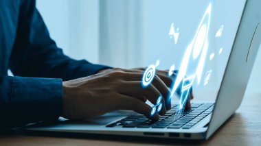 Modern bir çalışma ortamında teknoloji, yenilik ve yaratıcılığı temsil eden parlak dijital simgelerle dolu bir dizüstü bilgisayarda yazı yazmak. Dörtgen.