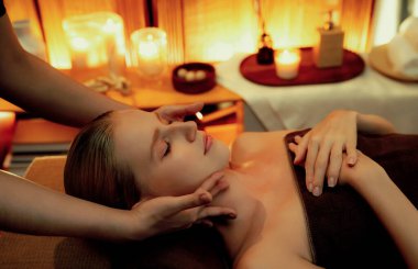 Beyaz kadın stres önleyici kafa masajı yapmaktan ve lüks otel veya otelde sıcak mum ışığında yüz güzelliği eğlencesi yapmaktan zevk alıyor. Sessiz.