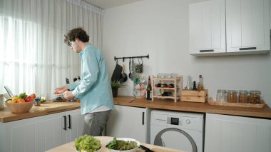 Mutlu baba yemek pişirirken müziğe geçiyor ve modern mutfakta öğle yemeği hazırlıyor. Aktif baba, sebze ve mutfak gereçleri ile çevrili sağlıklı yemek ya da salata yaparken şarkıyla dans ediyor. Pedagoji.