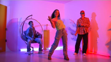 Çekici mutlu dansçı kameraya bakarken zeki kadın neon ışıkla kafiyeli hareket ediyor. Profesyonel İspanyol şarkıcı çeşitli arkadaşlarıyla renkli kıyafetler giyerken break dans yapıyor. Mutluluk.