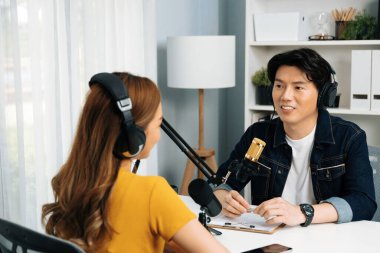 Gülümseyen radyo etkili sunucusu kulaklık takıyor kadın konuşmacı ile röportaj yapıyor sosyal medya internet sitesinden dinleyicilere bilgi paylaşıyor stüdyo kaydında sabah canlı yayın kanalı. İnfobahn.