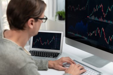 Bilgisayar ve dizüstü bilgisayarı kullanarak, çalışma masasındaki dinamik artırılmış borsa grafiğinin en yüksek kar değerini araştıran bir tüccar, modern ofisteki ekrandaki döviz kuru değerini analiz ediyor. Bireysel.