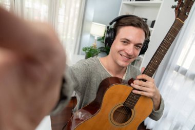 Akıllı şarkıcı görünümlü kamerada sunucu kanalı gitar tutarken, sosyal medya kanalında yayın yaparken, kulaklık takarken modern stüdyo kaydında video kaydedici olarak görülüyor. Bireysel.