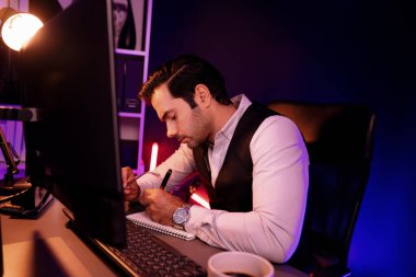 Stresli akıllı işadamı, kağıt işleri üzerine not pazarı verileri yazarak, gece geç saatlerde mor neon karanlık aydınlatma odasındaki disiplin ürünü hizmetlerinin çevrimiçi satış kanalını analiz ediyor. Tahmin et..