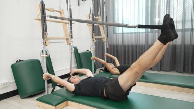 Bir grup müşteri, çekirdek dayanıklılığını ve bacak bağını geliştirmek için Cadillac reformatör makinesinde pilates egzersizleri yapıyor. Sağlıklı müşterilerin daha düşük poz verip kaldırma pozlarının üst görüntüsü. Sağlıklılık. Alışkanlık.