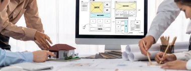 İç mimar tasarımcı grubu, daha kesin tasarım için planlar ve dizüstü bilgisayar ekran mimari yazılımı üzerinde birlikte tartışıyorlar. Modern ev tasarımı ve yenileme. İçgörü