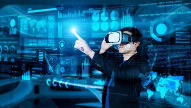 VR gözlüklü bir proje yöneticisi mali tabloyu ve ofisteki parlak mavi ışığı gösteriyor. Yetenekli iş adamı artırılmış gerçeklikten elde edilen verileri kullanarak pazarlama stratejisini kontrol edip planlıyor. Yaratıcılık.