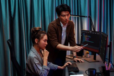 Bilgi teknolojisi geliştiricileri modern ofisteki neon ışık odasında verileri çevrimiçi olarak çalıştıran akıllı web sitesi geliştirme kodlayıcı sistemine işaret ediyorlar. İnfobahn.