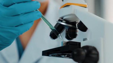 Laboratuvar kimya araştırmacısı mikroskop kullanarak yeni ilaç ya da tedavi geliştirir. Laboratuvar mikrobiyoloji ekipmanları ile bilimsel uzmanlık ile sağlık hizmetlerinin teknolojik gelişimi. Ağır çekim. Katı.