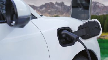 Elektro jeneratör sürücüsüyle enerji sürdürülebilir araba gücü, şarj istasyonunda şarj edilen batarya, ilerici seyahat konsepti için dağ zeminine sahip. Temiz ortamın sembolü olarak doğadaki EV otomobil.