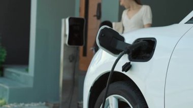 Evde şarj edilen elektrikli bir araçla okuldan yeni dönen anne ve kızın ilerici yaşam tarzı. Elektrikli araç, sürdürülebilir temiz enerjiyle çalışıyor..
