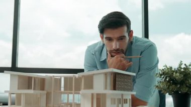 Akıllı Kafkasyalı mühendis veya proje yöneticisi ölçüm, teftiş, panorama penceresinin yanında, gökdelen manzaralı ev modeline bakın. Yönetici tasarım evi inşaatı. İzleme