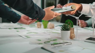 Bir grup profesyonel, yeşil bitkiler ve ekolojik bilinçli tasarım unsurları arasında yenilikçi sürdürülebilirlik stratejilerini tartışarak çağdaş bir ofis ortamında işbirliği yapmaktadır. SACTR