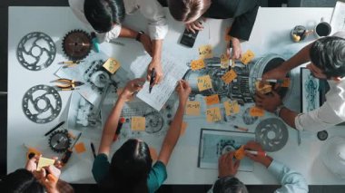 Üstten görünüşlü akıllı mühendis ekibi metal teçhizatlı, hesap makineli, yapışkan notlu türbin motor yapısı hakkında konuşuyor. Bir grup teknisyen toplantıda not alıyor. Hizalama.