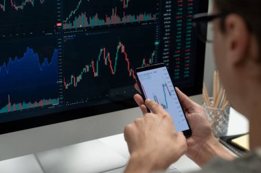 Akıllı borsa yatırımcıları ekranda akıllı telefon ile piyasa borsasını işaret ederek dizüstü bilgisayarın yanı sıra en yüksek dinamik yatırım oranını göstererek, modern işyerindeki veri planlamasına odaklanıyorlar. Bireysel.