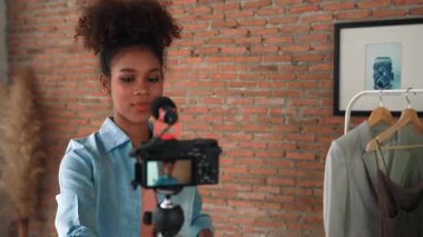 Kadın nüfuzlu kişi canlı yayında video görüntülerini çekiyor. Kıyafetler sosyal medya ya da blog için çok önemli. Stüdyo ışıklandırmalı mutlu genç kız çevrimiçi pazarlama oturumu yayını için..