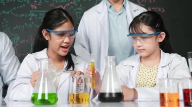 Zeki öğretmen, çeşitli deneyler yapan çocuklara destek olur ve onlarla ilgilenir. Karışık ırktan lise öğrencisi masadaki biyokimyasal sıvıyı mikroskop ile inceliyor. Öğretim