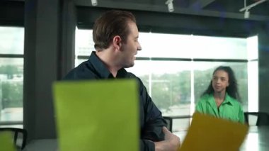 Profesyonel iş adamları yaratıcı pazarlama fikrini modern ofiste tartışırlar. İş adamları cam tahtada yapışkan notlar kullanarak finansal plan üzerinde çalışıyor. Yönlendirici.