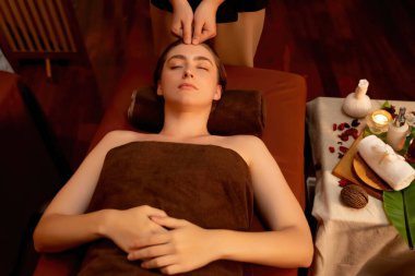 Beyaz kadın stres önleyici kafa masajı yapmaktan ve lüks otel veya otelde sıcak mum ışığında yüz güzelliği eğlencesi yapmaktan zevk alıyor. Sessiz.